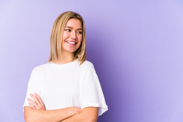 Joven mujer caucásica rubia aislada sonriendo confiada con los brazos cruzados.