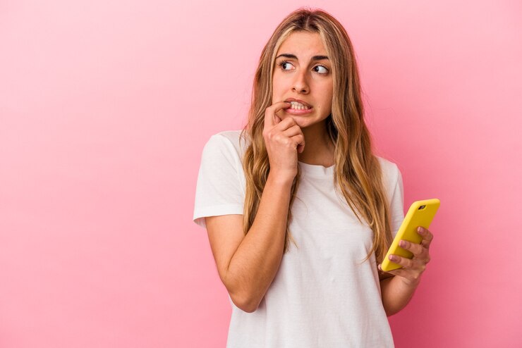 Foto joven mujer caucásica rubia sosteniendo un teléfono móvil amarillo aislado relajado pensando en algo mirando un espacio de copia