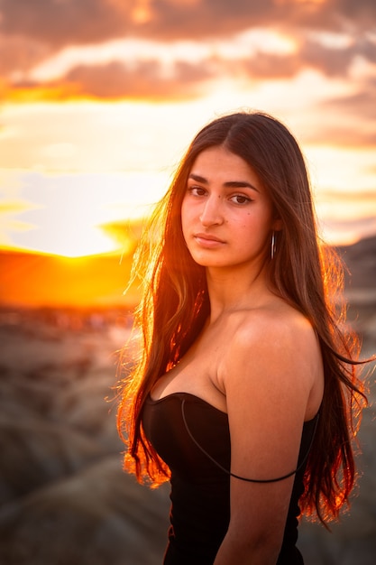 Foto joven mujer caucásica con un sexy vestido negro al atardecer en las bardenas reales, navarra, país vasco.