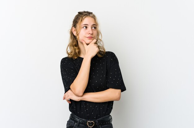 Joven mujer caucásica sobre fondo blanco pensando y mirando hacia arriba, siendo reflexivo, contemplando, teniendo una fantasía.