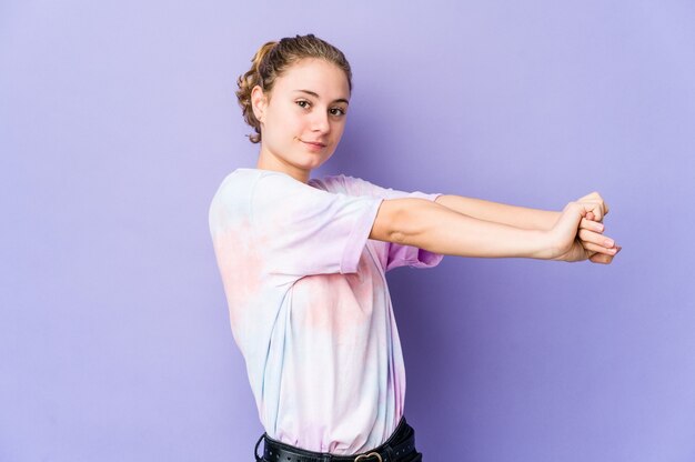 Foto joven mujer caucásica sobre fondo púrpura estirando los brazos, posición relajada.