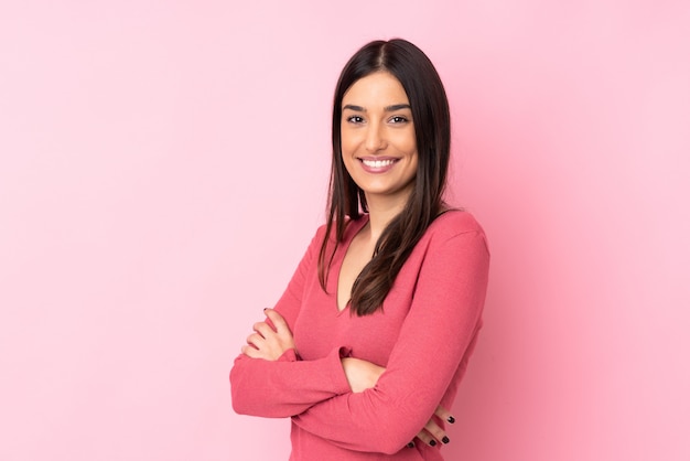 Joven mujer caucásica sobre pared aislada con los brazos cruzados y mirando hacia adelante