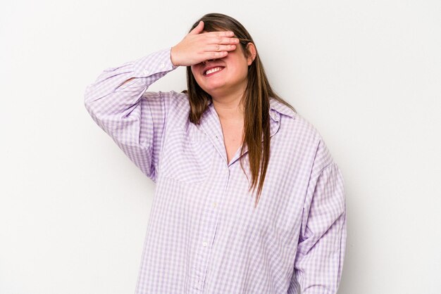 Foto joven mujer caucásica con sobrepeso aislada de fondo blanco cubre los ojos con las manos sonríe ampliamente esperando una sorpresa