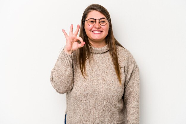 Joven mujer caucásica con sobrepeso aislada sobre fondo blanco alegre y confiada mostrando un gesto correcto