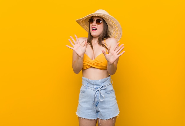 Joven mujer caucásica con un sombrero de paja, mirada de verano rechazando a alguien mostrando un gesto de disgusto.