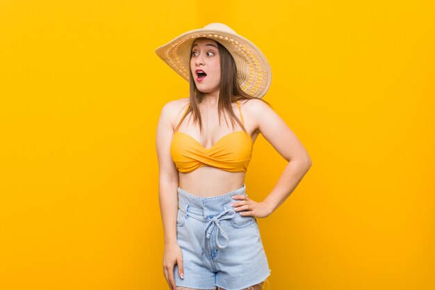 Joven mujer caucásica con un sombrero de paja, mirada de verano se sorprendió por algo que ha visto.