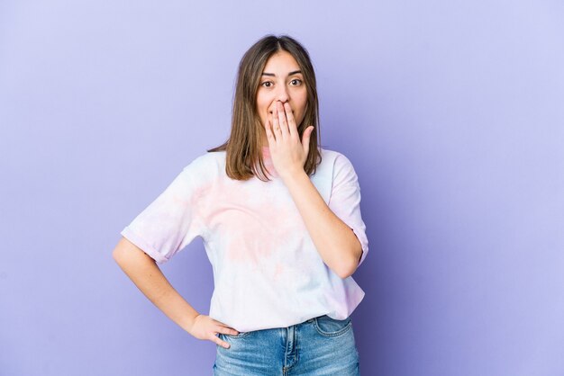 Joven mujer caucásica sorprendida, tapándose la boca con las manos, ansiosa por descubrir algo nuevo.