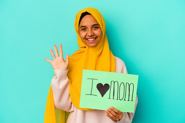 Foto joven mujer caucásica sosteniendo un amo a mamá aislado sobre fondo rosa sonriendo alegre mostrando el número cinco con los dedos.