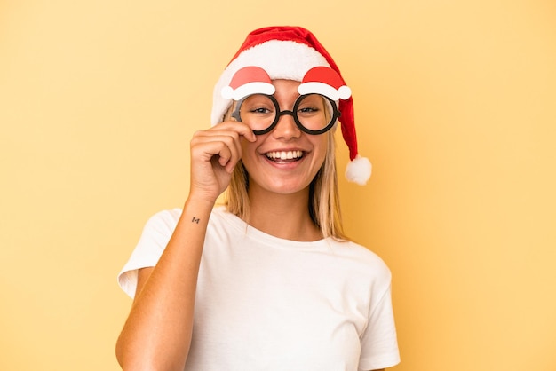 Joven mujer caucásica sosteniendo un apoyos de Navidad aislado sobre fondo amarillo