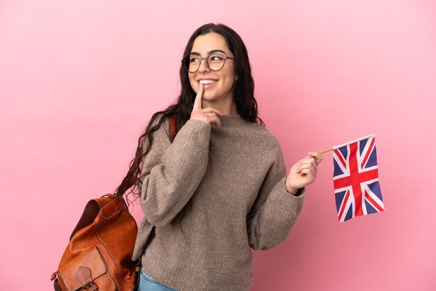 Joven mujer caucásica sosteniendo una bandera de Reino Unido aislada