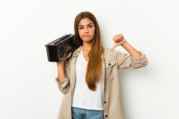 Joven mujer caucásica sosteniendo un blaster guetto mostrando un gesto de aversión, pulgares hacia abajo. concepto de desacuerdo.