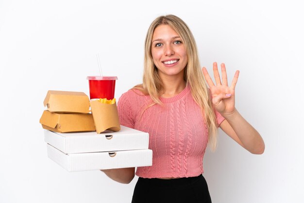 Joven mujer caucásica sosteniendo comida gorda aislada de fondo azul feliz y contando cuatro con los dedos