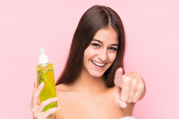 Joven mujer caucásica sosteniendo una crema hidratante con aloe vera aislado sonrisas alegres apuntando al frente