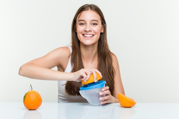 Joven mujer caucásica sosteniendo un exprimidor de naranja