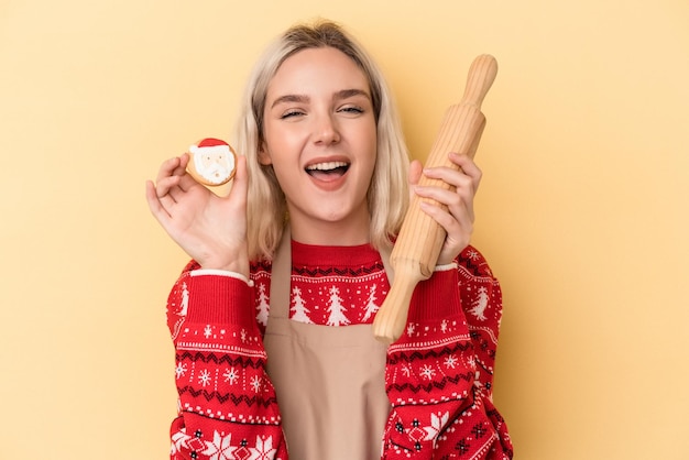 Joven mujer caucásica sosteniendo galletas de Navidad aislado sobre fondo amarillo