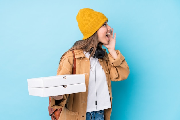 Joven mujer caucásica sosteniendo pizzas aisladas gritando y sosteniendo la palma cerca de la boca abierta.