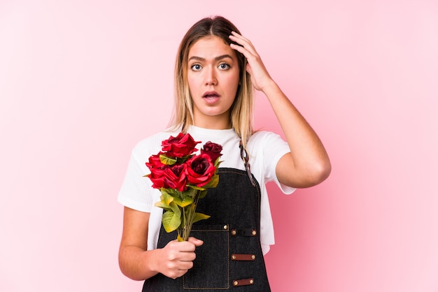 Joven mujer caucásica sosteniendo rosas sorprendiéndose, ha recordado una reunión importante.