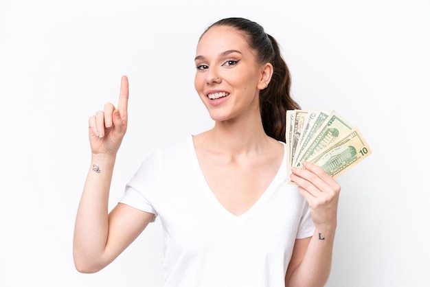 Foto joven mujer caucásica tomando un montón de dinero aislado en fondo blanco señalando una gran idea