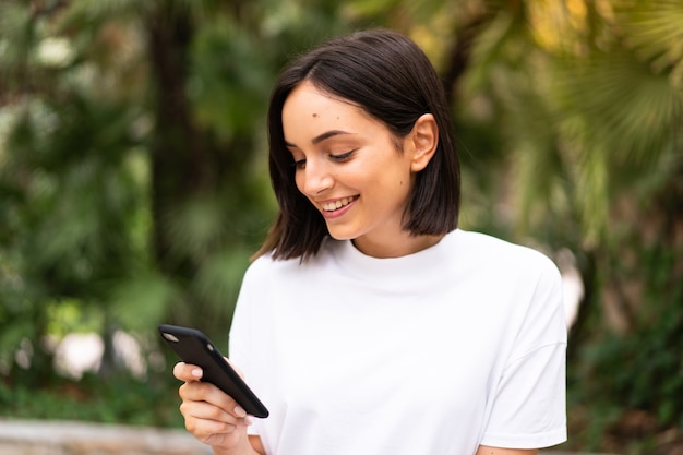 Joven mujer caucásica usando un teléfono al aire libre