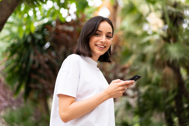 Joven mujer caucásica usando un teléfono al aire libre