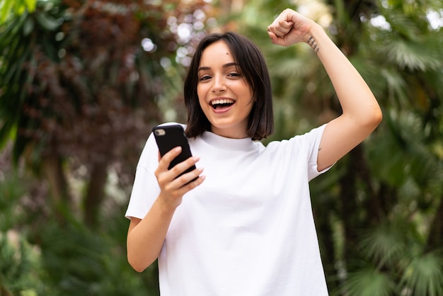 Joven mujer caucásica usando un teléfono al aire libre