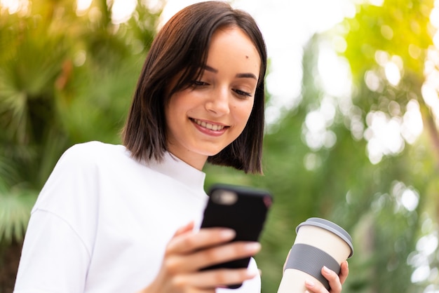 Joven mujer caucásica usando un teléfono al aire libre