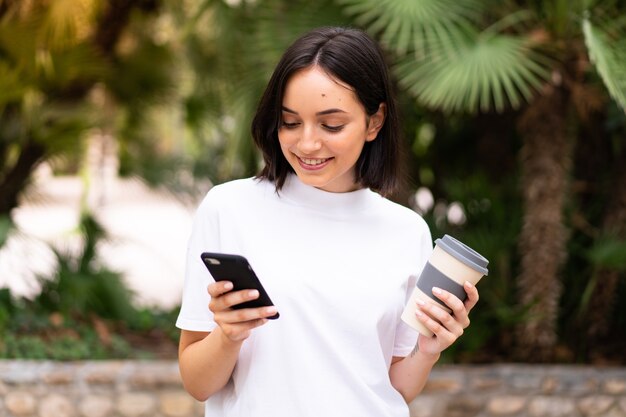 Joven mujer caucásica usando un teléfono al aire libre