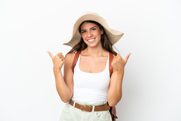 Joven mujer caucásica vistiendo una Pamela en vacaciones de verano aislado sobre fondo blanco con gesto de pulgar hacia arriba y sonriente