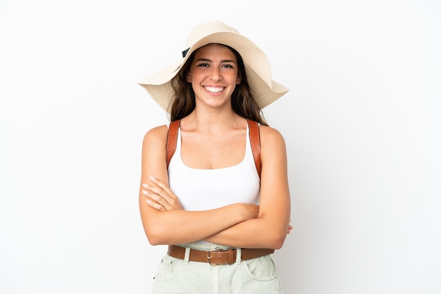 Joven mujer caucásica vistiendo una Pamela en vacaciones de verano aislado sobre fondo blanco manteniendo los brazos cruzados en posición frontal