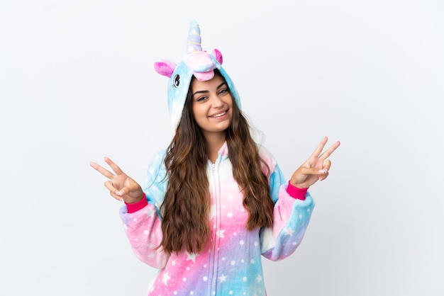 Joven mujer caucásica vistiendo un pijama de unicornio aislado sobre fondo blanco mostrando el signo de la victoria con ambas manos