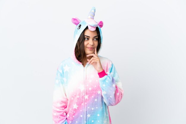 Joven mujer caucásica vistiendo un pijama de unicornio aislado sobre fondo blanco pensando en una idea mientras mira hacia arriba