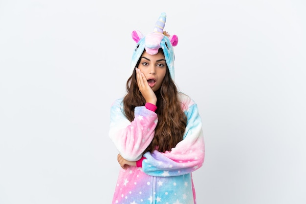 Joven mujer caucásica vistiendo un pijama de unicornio aislado sobre fondo blanco sorprendido y conmocionado mientras mira a la derecha