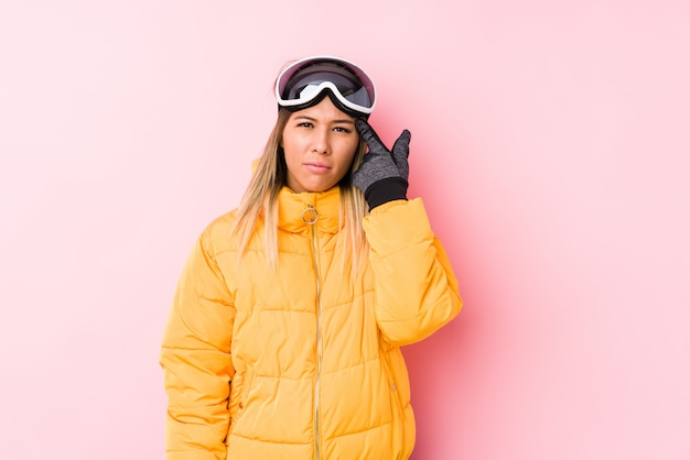 Joven mujer caucásica vistiendo una ropa de esquí en una pared de color rosa que muestra un gesto de decepción con el dedo índice.