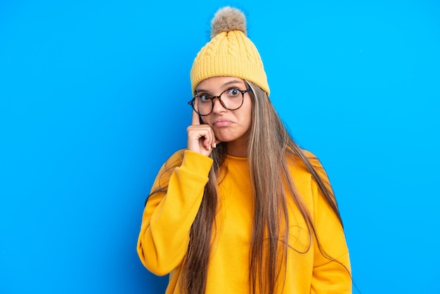 Joven mujer caucásica vistiendo ropa de invierno aislado sobre fondo azul pensando en una idea