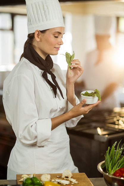 Joven mujer chef oliendo hierba