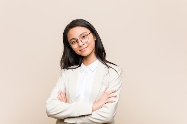 Joven mujer china de negocios que se siente segura, cruzando los brazos con determinación.