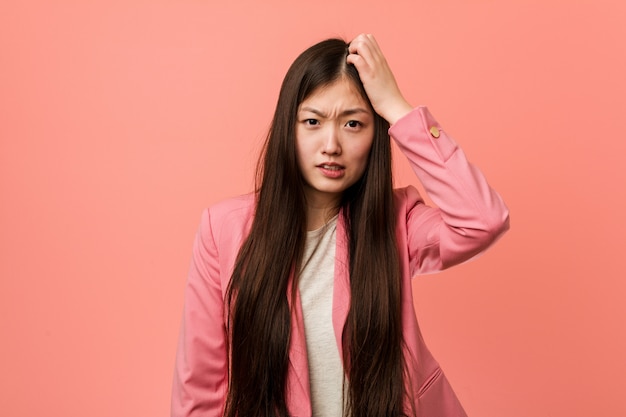 Joven mujer china de negocios con traje rosa se sorprendió, ha recordado una reunión importante.