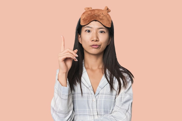 Joven mujer china en pijama máscara teniendo alguna gran idea concepto de creatividad