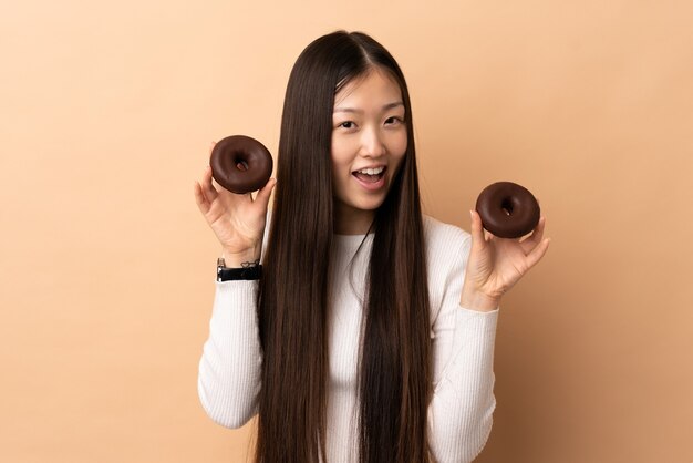 Joven mujer china sobre donas de explotación aislada con expresión feliz