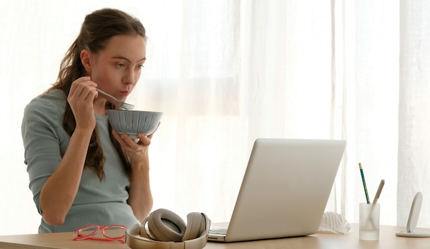 Joven mujer comiendo gachas en la mesa en la sala de estar