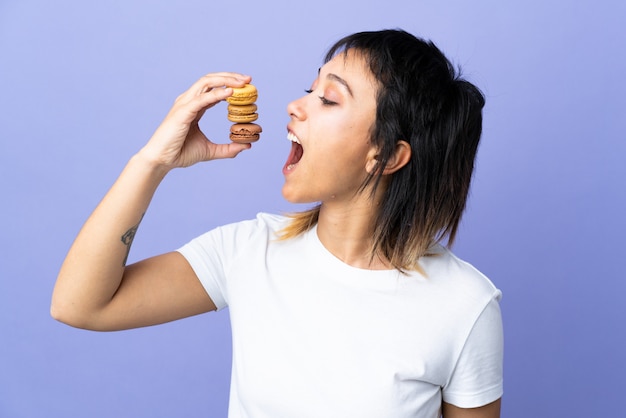 Joven mujer comiendo macarrones sobre fondo aislado