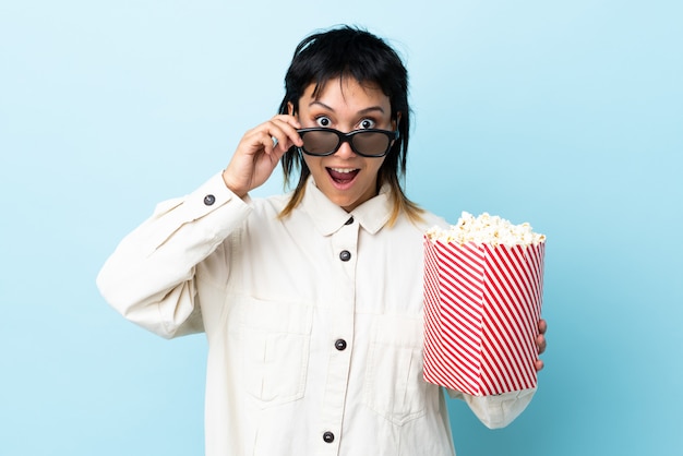 Joven mujer comiendo palomitas sobre pared aislada