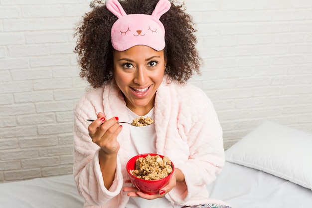 Joven mujer comiendo un tazón de cereal en la cama