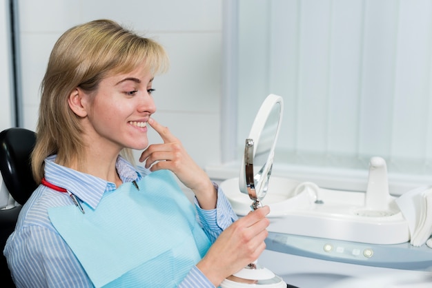 Joven mujer comprobando sus dientes en el espejo