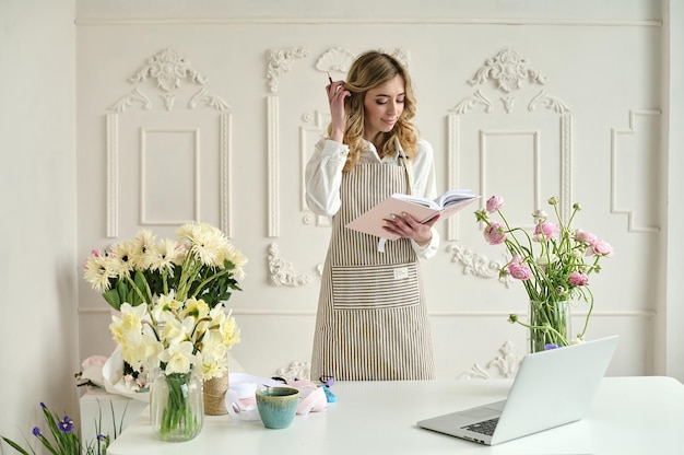 Joven mujer creativa en una floristería usando una computadora portátil