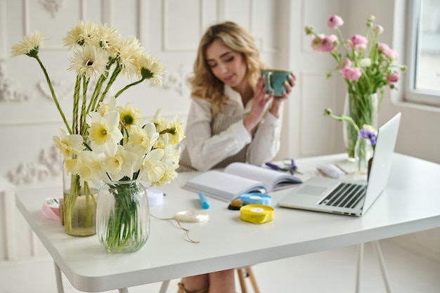 Joven mujer creativa en una floristería usando una computadora portátil