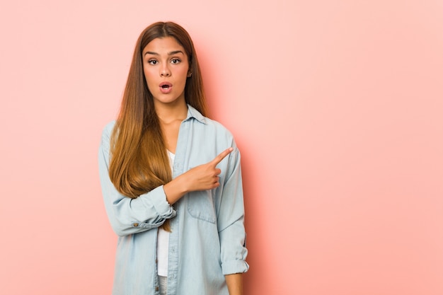 Joven mujer delgada apuntando hacia el lado