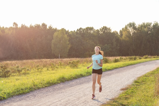 Joven mujer delgada con cuerpo perfecto corriendo en un parque