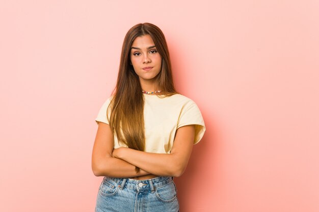 Joven mujer delgada infeliz mirando en cámara con expresión sarcástica.