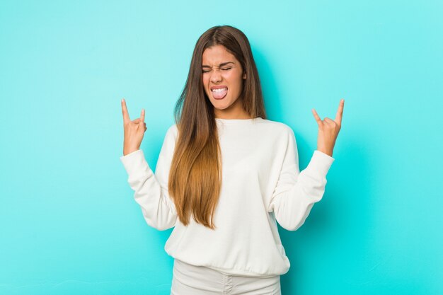 Joven mujer delgada mostrando gesto de rock con los dedos